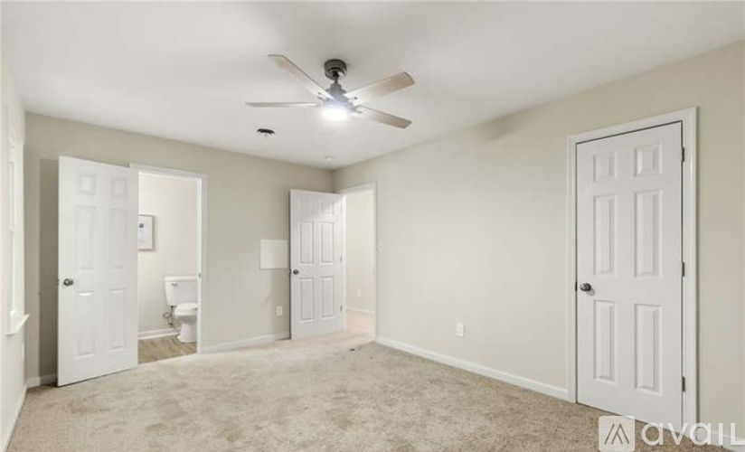 A spacious room with a ceiling fan and carpeted floor.