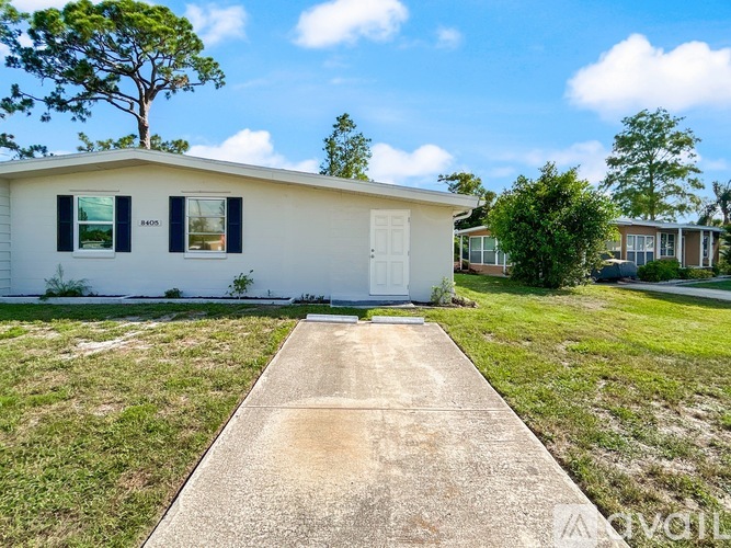 A white house with a concrete pathway leading to the front door.