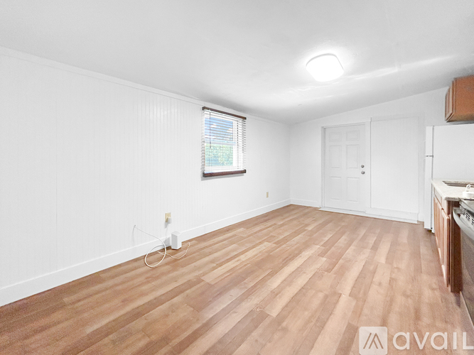 A room with wooden flooring and a window with blinds.
