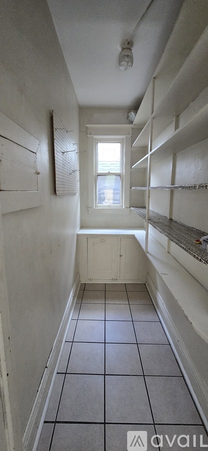 A long hallway with white walls and tile flooring.