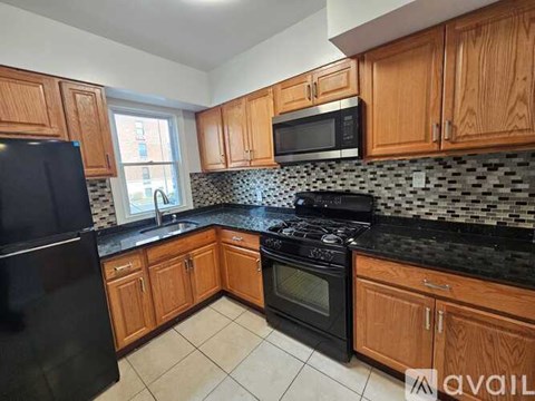 A kitchen with black appliances and wooden cabinets.