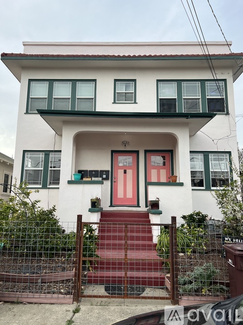 A white house with a red door and a red staircase.