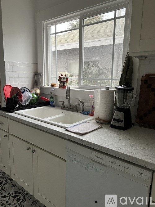 A kitchen with a white dishwasher and a window.