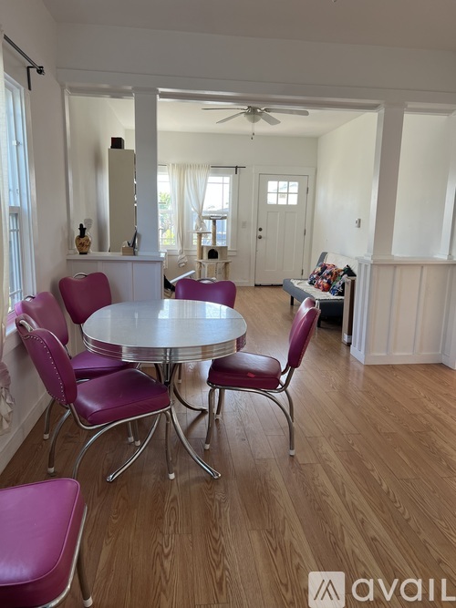 A dining room with a round table and purple chairs.