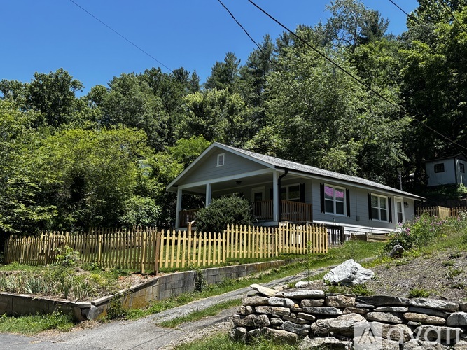 A house with a white fence and a stone wall in front.