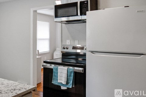 A kitchen with a white refrigerator, black stove, and a microwave above the oven.
