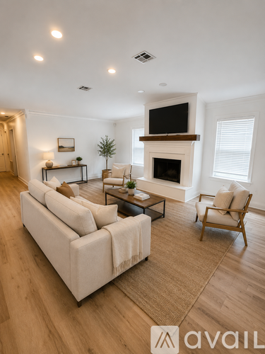 A living room with a white couch, a fireplace, and a television mounted above it.