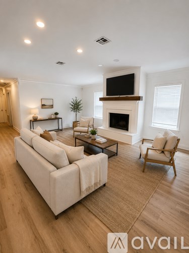 A living room with a white couch, a fireplace, and a television mounted above it.