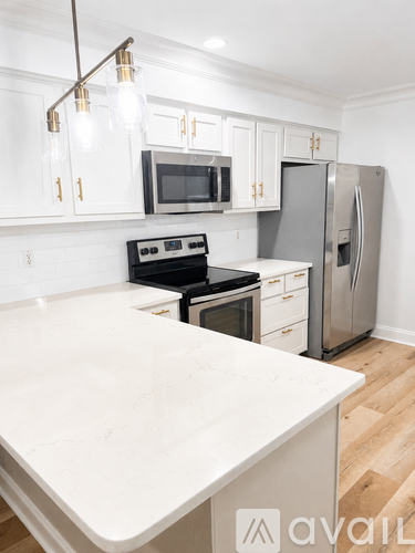 A kitchen with a white counter top and stainless steel appliances.