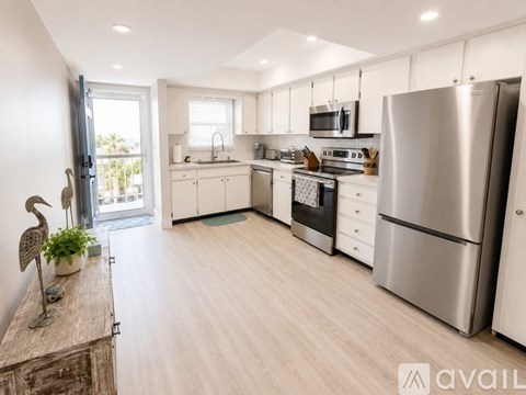 A modern kitchen with stainless steel appliances and wooden flooring.