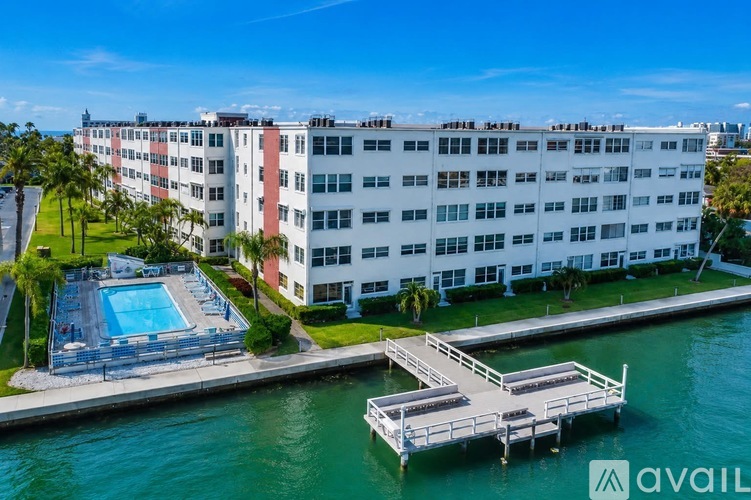A large white building with a pool and dock in front.