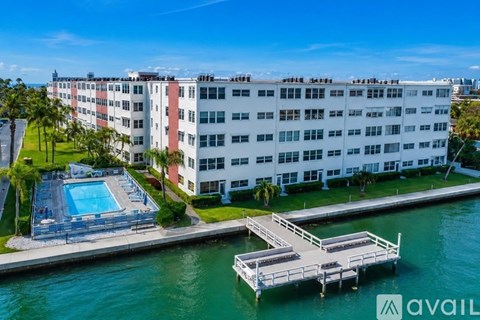 A large white building with a pool and dock in front.
