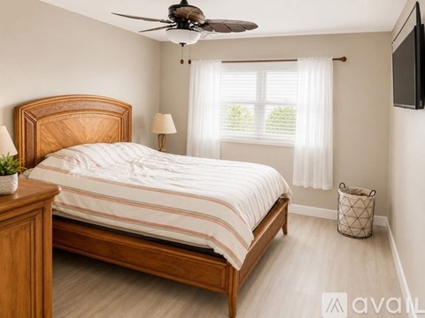 A bedroom with a bed, nightstand, and window with white curtains.