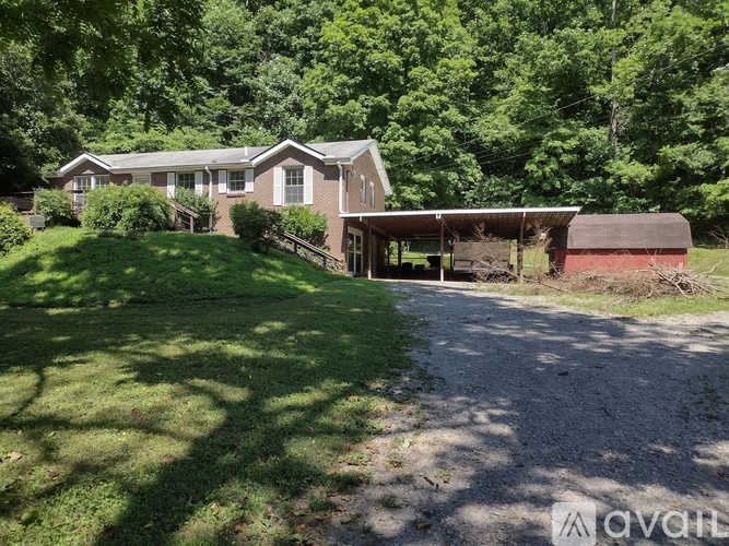 A house with a driveway and a covered porch is surrounded by trees.