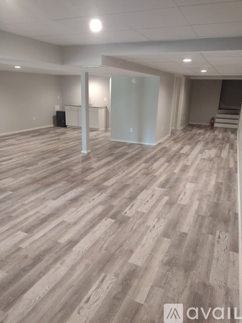 A spacious room with wooden flooring and white walls.