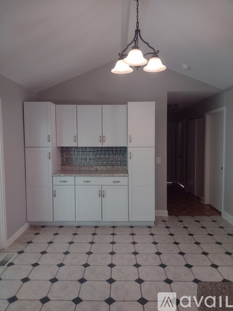 A kitchen with white cabinets and a checkered floor.