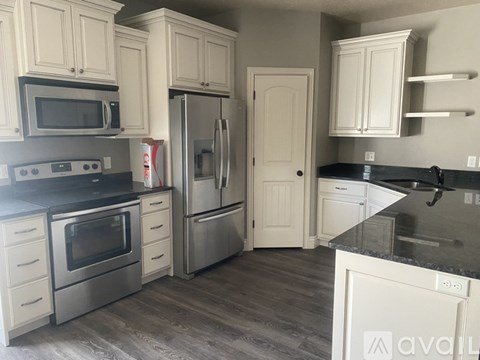 A kitchen with white cabinets and a black countertop.
