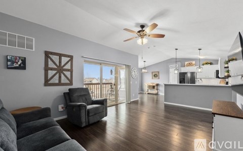 A living room with a grey couch and a ceiling fan.