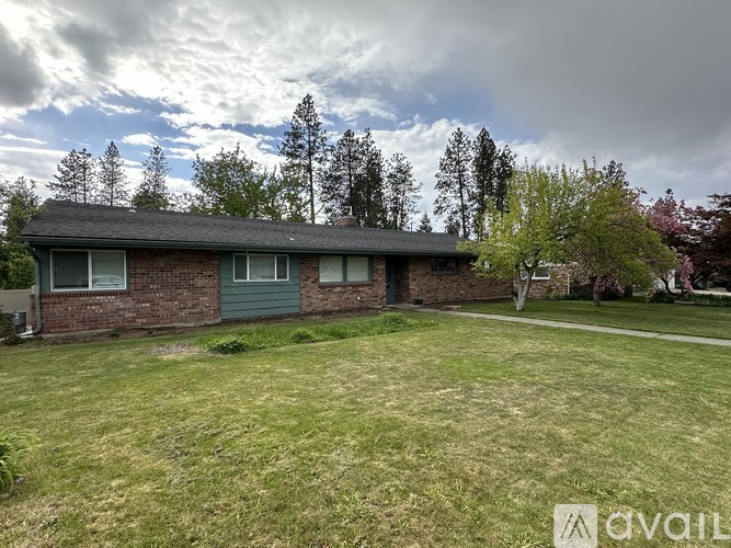 A house with a green lawn and trees in the background.
