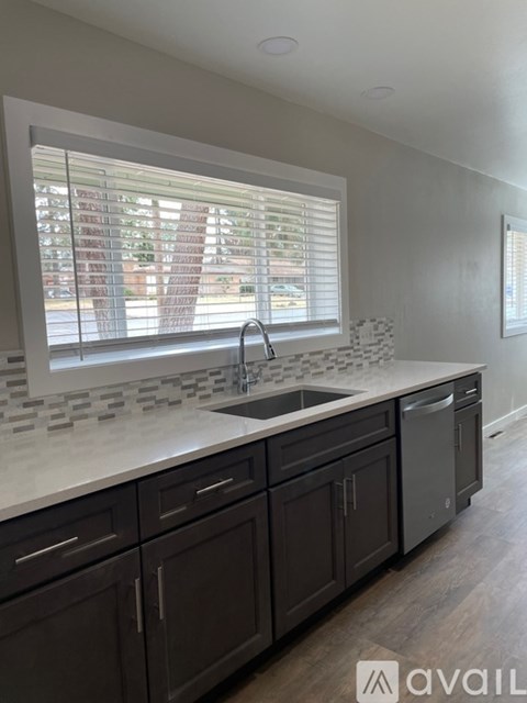 A kitchen with dark brown cabinets and a marble countertop.