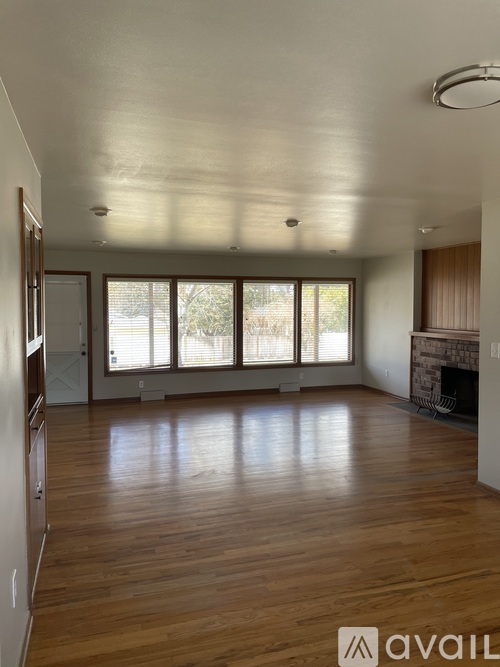 A spacious living room with wooden floors and a fireplace.