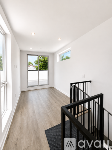 A white room with wooden floors and a balcony with a black railing.