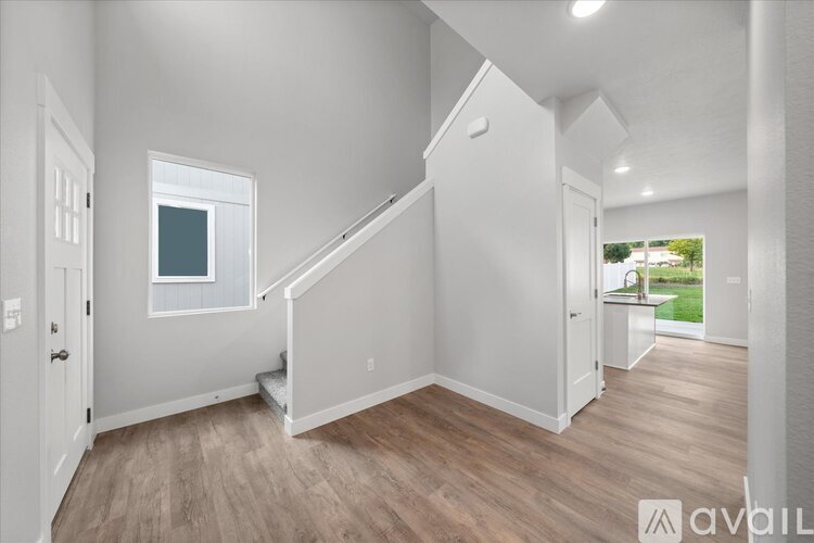A spacious, empty room with light wood flooring and white walls.