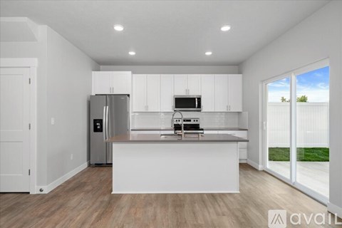 A modern kitchen with white cabinets and a wooden floor.