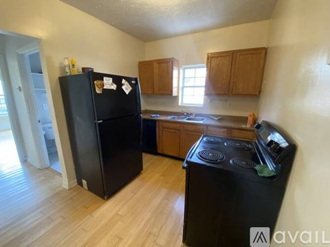 A black fridge and stove in a kitchen with wooden cabinets.