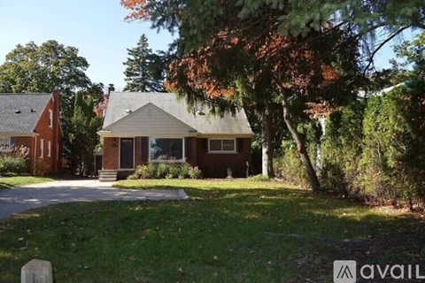 A house with a front yard and a tree with red leaves.