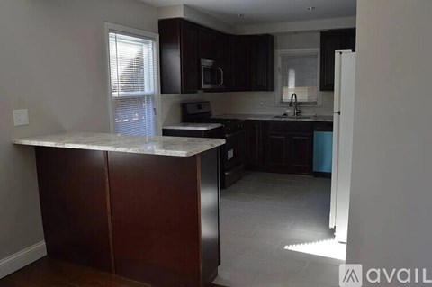 A kitchen with a marble island and dark wood cabinets.