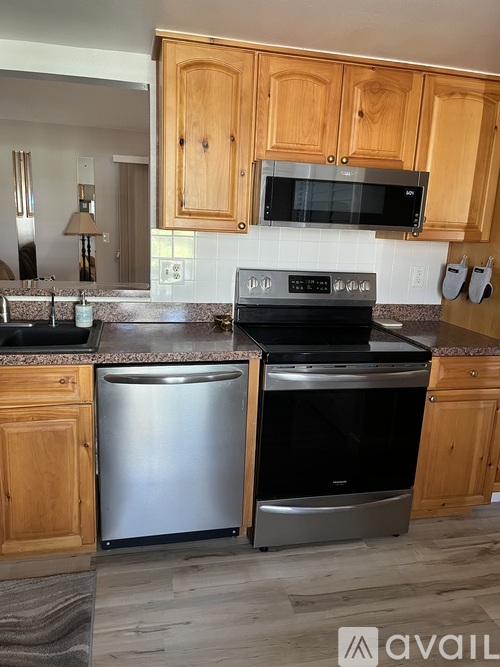A kitchen with wooden cabinets and a stainless steel dishwasher and oven.
