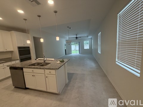 A spacious kitchen with white cabinets and a granite countertop.