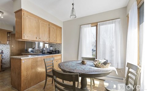 A kitchen with wooden cabinets and a table with chairs.