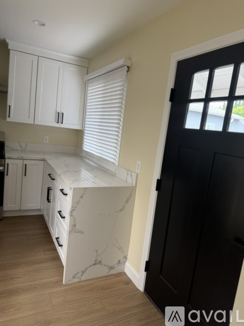A kitchen with white cabinets and a black door.