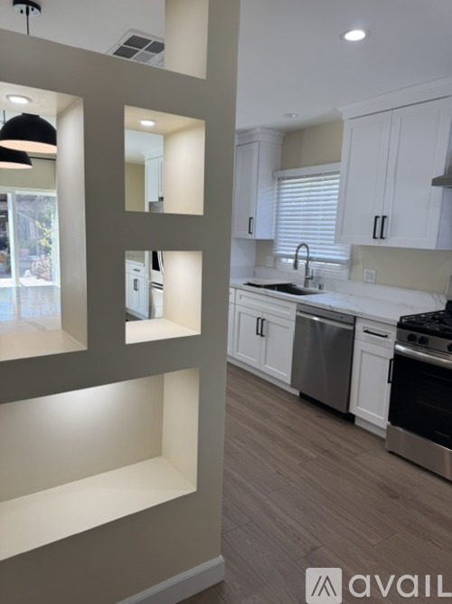A modern kitchen with white cabinets and a wooden floor.