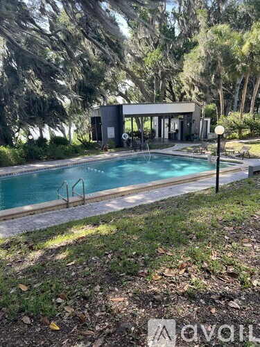 A pool surrounded by trees and a building in the background.