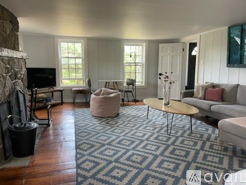 A living room with a stone fireplace and a rug on the floor.