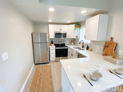 A kitchen with white cabinets and a stainless steel refrigerator.