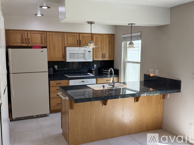A kitchen with a refrigerator, microwave, and a counter with a sink.