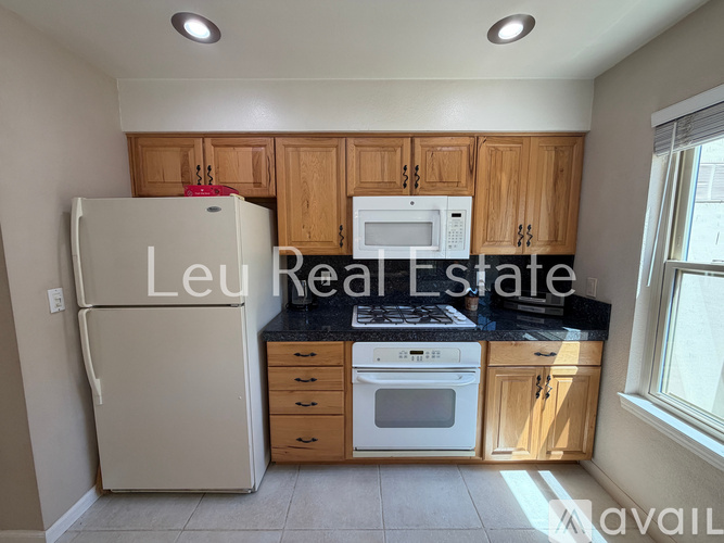 A kitchen with a refrigerator, microwave, oven, and cabinets.