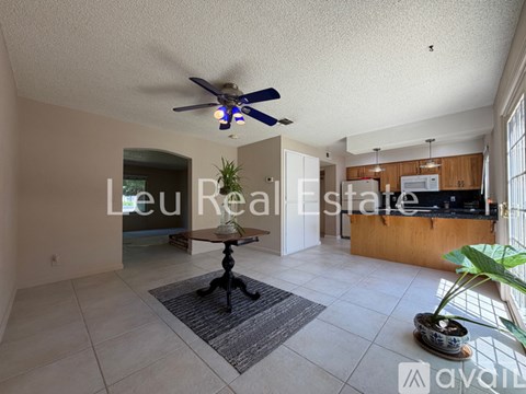 A living room with a ceiling fan and a rug in the middle.