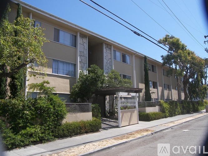 A street view of apartment buildings with green trees and bushes.