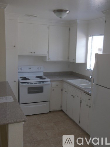 A kitchen with white cabinets and a stove top oven.