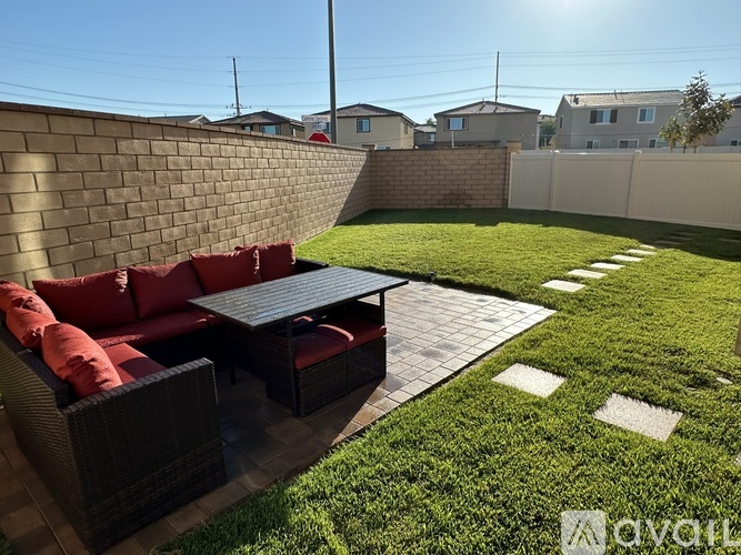 A patio with a table and chairs is surrounded by a brick wall and a grassy area.