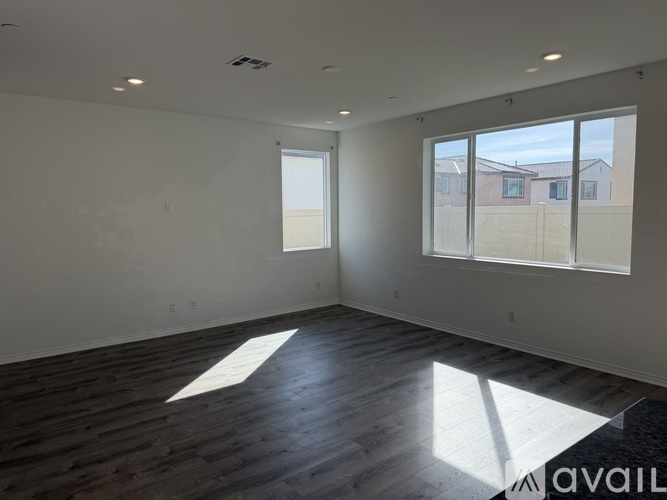 A spacious room with wooden floors and large windows.