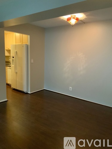 A room with a white wall and a white fridge.