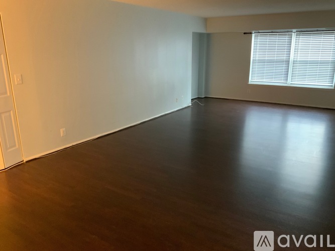 A room with wooden flooring and a window with blinds.