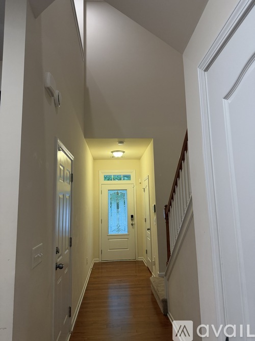 A hallway with a staircase on the right and a door on the left.
