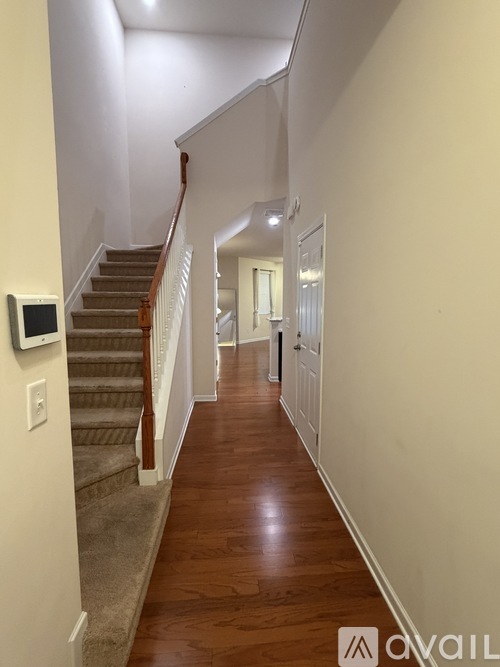 A hallway with a staircase and a digital display on the wall.